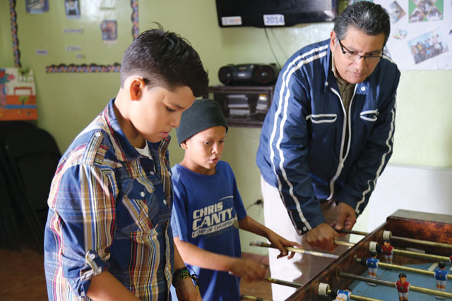 Vision 2016 Scheiber 1 Fighting gangs one youth at a time Father Alexis Zúñiga, S.T. plays foosball with boys at the Outreach Center for My Neighborhood.