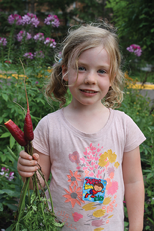 Vision 2017 Tomshack CSJ-MN4 Gardens a little girl holds vegetables in Celeste’s Dream Community Garden